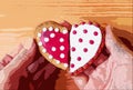 Couple`s hand holding two half heart shaped cookies attach on wooden background Royalty Free Stock Photo
