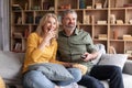 Couple's Leisure. Positive Middle Aged Spouses Laughing While Watching Tv At Home Royalty Free Stock Photo