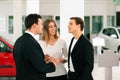 Couple with salesman at car dealer