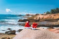 Couple of santa claus hat on tropical exotic paradise sandy beach with ocean waves and rocky coastline in background Royalty Free Stock Photo