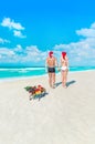 Couple in Santa hats walking back at sea beach with sleds, Chris Royalty Free Stock Photo