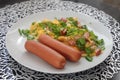 A couple of sausages with scrambled eggs and chopped green onions. Omelet with sausage.