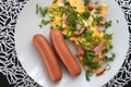 A couple of sausages with scrambled eggs and chopped green onions. Omelet with sausage.