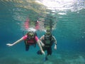 Couple scuba diving under crystal clear water with tank, fins and visor happy swim and share their love doing exercise and living