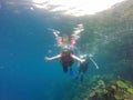 Couple scuba diving under crystal clear water with tank, fins and visor happy swim and share their love doing exercise and living