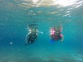 Couple scuba diving under crystal clear water with tank, fins and visor happy swim and share their love doing exercise and living