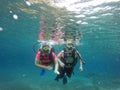 Couple scuba diving under crystal clear water with tank, fins and visor happy swim and share their love doing exercise and living