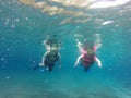 Couple scuba diving under crystal clear water with tank, fins and visor happy swim and share their love doing exercise and living