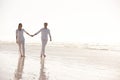 Couple, sea and holding hands while walking on beach, travel and commitment with trust and bonding outdoor. Love, care Royalty Free Stock Photo