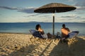 Couple secrets fantasy. Couple in love at sea resort sits on loungers under umbrella on sand beach. Couple on vacation