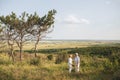 A couple of senior adults in the white linen dress is standing outdoors, in the hands a bouquet of flowers, three Royalty Free Stock Photo