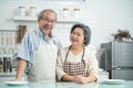 Couple senior Asian elder happy living in home kitchen. Grandfather hug grandmother with happiness and smile enjoy retirement life Royalty Free Stock Photo