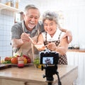 Couple senior Asian elder happy living in home kitchen. Grandfather wiping grandmother mouth after eating bread with jam vlog vdo Royalty Free Stock Photo