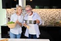 Couple senior caucasian husband and wife in casual dress standing, cooking salad with relaxation in kitchen at house. Happy Royalty Free Stock Photo