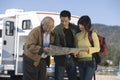 Couple and senior father reading map outside RV Royalty Free Stock Photo