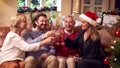 Couple With Senior Parents On Sofa Making A Toast With Champagne To Celebrate Christmas At Home Royalty Free Stock Photo