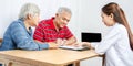 Couple senior patient in office filling out medical document form on a clipboard with female doctor, Patient listening receiving Royalty Free Stock Photo