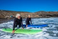 Couple of seniors at the beach with black wetsuits holding a surftable ready to go surfing a the beach - active mature and retired