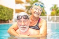Couple of seniors enjoying summer and having fun together in the pool swimming and smiling looking at the camera - cheerful happy Royalty Free Stock Photo