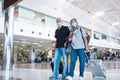 Couple of seniors and mature people walking in a airport with their luggage and trolleys - vacations and traveling in covid-19 and