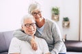 Couple of seniors smiling and looking at the camera - woman hogging at man with love on the sofa - indoor Royalty Free Stock Photo