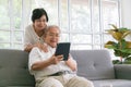 Couple of seniors smiling and looking at the same tablet hugged on the sofa Royalty Free Stock Photo