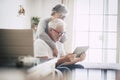 Couple of seniors smiling and looking at the same tablet hugged on the sofa - indoor, at home concept - caucasians mature and Royalty Free Stock Photo