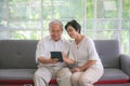 Couple of seniors smiling and looking at the same tablet on the sofa Royalty Free Stock Photo