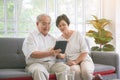 Couple of seniors smiling and looking at the same tablet on the sofa Royalty Free Stock Photo