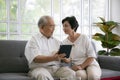 Couple of seniors smiling and looking at the same tablet on the sofa. Mature couple making a selfie or video call