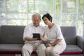 Couple of seniors smiling and looking at the same tablet on the sofa. Mature couple making a selfie or video call Royalty Free Stock Photo