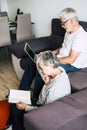 Couple of seniors smiling and looking at the tablet - woman hogging at man with love on the sofa - indoor - showing Royalty Free Stock Photo