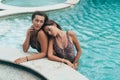 Couple of sexy models in leopard swimsuits relaxing near swimming pool