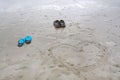 Couple shoes on beach with painted heart on sand by the sea in a summer day