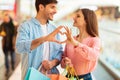 Couple Shopping Making Fingers Heart Holding Shopper Bags In Mall