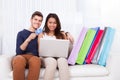 Couple shopping online with bags on sofa Royalty Free Stock Photo