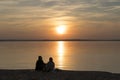 Couple on the shore of the lake during summer sunset and beautiful evening sky. Romance, love, relationships, friendship Royalty Free Stock Photo