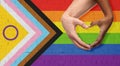 couple showing hand heart over progress pride flag