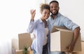 Couple Showing Key Holding Moving Box Standing In New Home