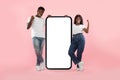 Couple showing white empty smartphone screen and making win gesture Royalty Free Stock Photo
