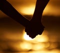 Couple, silhouette and holding hands at sunset on a beach for vacation or holiday outdoor. Closeup of man and woman in Royalty Free Stock Photo