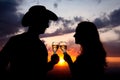 Couple Silhouettes clanging glasses at sunset Royalty Free Stock Photo