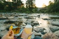 Couple sit near mountain river with chips and beer