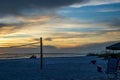 Couple sits on the beach together while watching the sunset, amomgst volleyball net, beach chairs and firepit Royalty Free Stock Photo