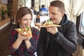 Couple sits in a pizzeria and eats pizza, a guy and a girl dine fast food, smile and relax in a restaurant