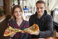 Couple sits in a pizzeria and eats pizza, a guy and a girl dine fast food, smile and relax in a restaurant