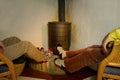 couple sits by warming cast iron wood stove, warming and drying their feet in socks, Energy Conservation and Ecology concept,