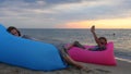 Couple sitting on air bed on beach at sunrise. Man and woman having relaxing time on vacation. Psychology, relationship