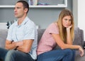 Couple sitting back to back after a fight on the couch with woman looking at camera Royalty Free Stock Photo