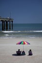 Couple Sitting on Beach with Beach Umbrella Royalty Free Stock Photo